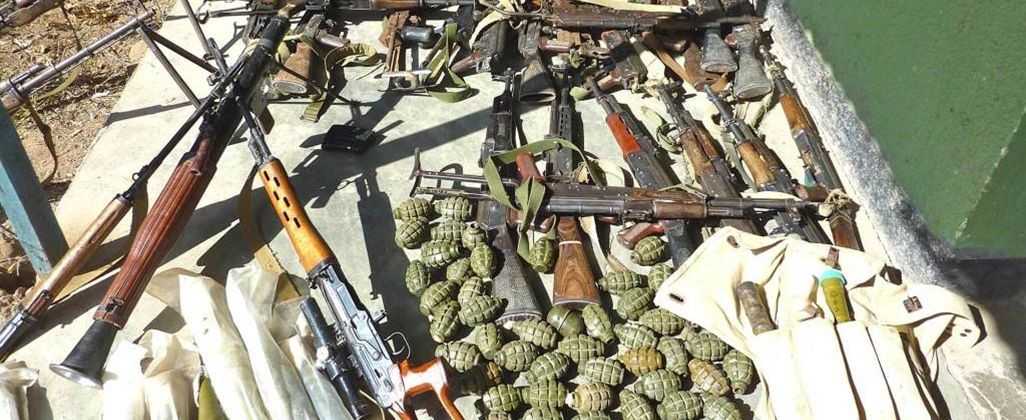 The photo shows numerous Small Arms and Light Weapons laid out on the ground.