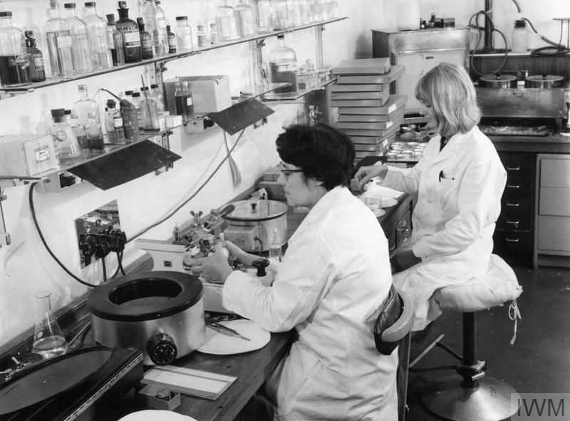 Two women wearing white lab coats work in a laboratory